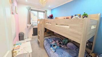 A child's bedroom with a bunk bed, a desk, and a window.
