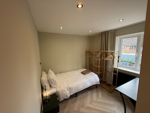 A bedroom with a bed, a desk, a hanging clothes rack, and a radiator. - 5 Bed Home - Contractors & Professionals - Wifi (Luton)