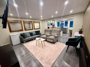 A modern living room with a sofa, armchairs, a coffee table, and a dining area with a table and chairs. - 5 Bed Home - Contractors & Professionals - Wifi (Luton)