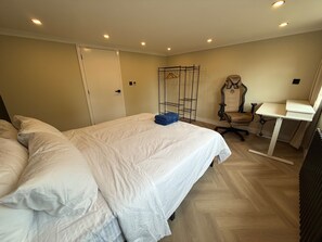 A hotel room with a large bed, a desk with a chair, and a radiator. - 5 Bed Home - Contractors & Professionals - Wifi (Luton)