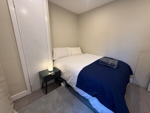 Ein Schlafzimmer mit einem Bett, einem Nachttisch mit einer Lampe und einem kleinen Teppich.