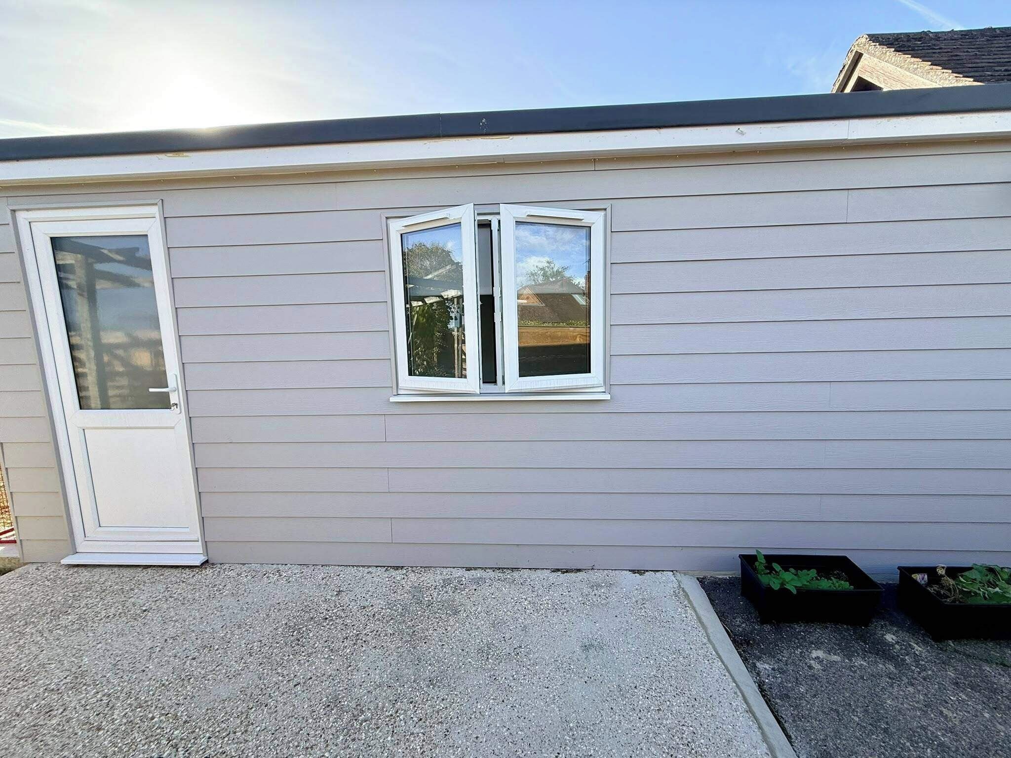 Un bâtiment d’un seul étage avec une porte blanche et une fenêtre.