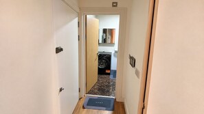 A narrow hallway leading to a laundry area with a washing machine and a small mat on the floor. - Acton Studio, Sleeps 2 with WiFi (London)