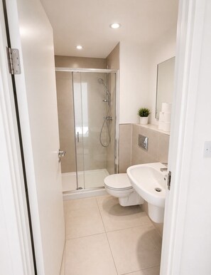 A modern bathroom with a glass-enclosed shower, a toilet, and a sink. - Two bedroom two bathroom at Croydon city center (Croydon)