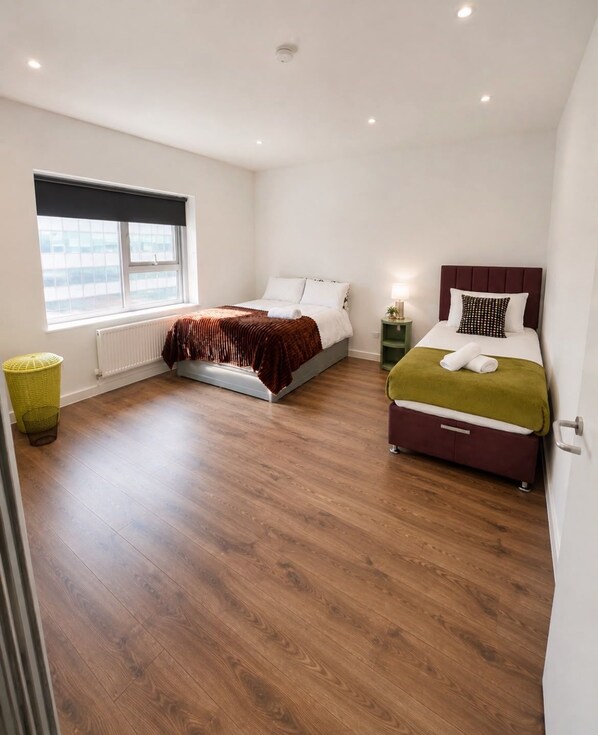 A hotel room with two beds, a window, a radiator, and a wooden floor. - Two bedroom two bathroom at Croydon city center (Croydon)