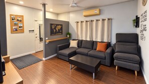 Una sala de estar moderna con un sofá gris, un sillón a juego, una mesita de centro y un mapa del mundo en la pared.