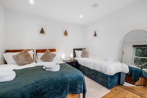 A hotel room with two beds, a large mirror, and three framed Christmas trees on the wall. - Apartment Sleeps 7 with Wifi (London)