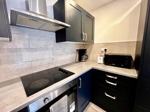 A modern kitchen with a built-in stove, a coffee maker, a toaster, and a microwave. - Apartment Sleeps 5 near HIgh Street (Croydon)