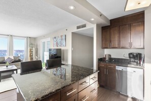 A modern kitchen with granite countertops, stainless steel appliances, and dark wooden cabinets. - Downtown, 20th floor, river view, gym, free parking (Saskatoon)