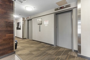 An elevator with a digital display, a wall-mounted emergency phone, and a carpeted floor. - Downtown, 20th floor, river view, gym, free parking (Saskatoon)