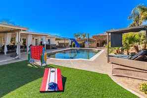 A swimming pool with a slide, a red and white mat, and a covered seating area. - Pickleball in Paradise | Sleeps 16, Free Pool Heat, Putting Green, Volleyball, & Games (Paradise Valley)