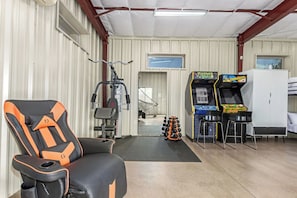A gym with exercise equipment, a gaming area with arcade machines, and a bunk bed. - Pickleball in Paradise | Sleeps 16, Free Pool Heat, Putting Green, Volleyball, & Games (Paradise Valley)