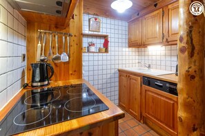 A kitchen with a black stovetop, wooden cabinets, and a Bosch dishwasher. - Les Abeillos - Les Croes (BONNEVAL SUR ARC)