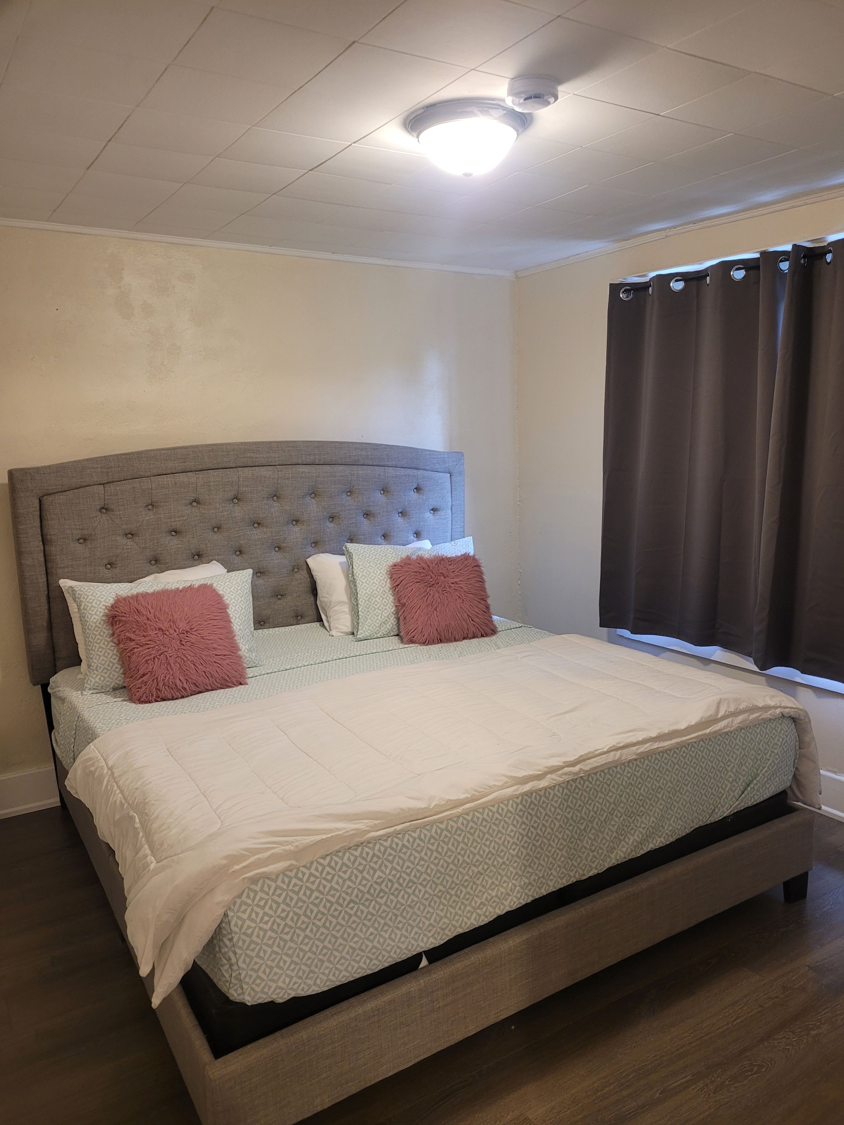 Una cama individual con cabecera capitonada, edredón blanco y ropa de cama estampada.