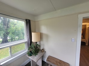 A room with a window, a lamp, a small table, and a bench.