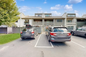 A parking lot with two cars, a fence, and a building with a garage. - 2BR Ketchum condo with fast WiFi, patio, and easy mountain access. (Ketchum)