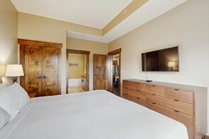 A hotel room with a large bed, wooden wardrobe, a TV mounted on the wall, and a bathroom visible through an open door. - Trailhead Lodge #5116 condo with fireplace, under three miles from downtown (Steamboat Springs)