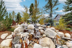 A natural rock formation with a small waterfall, surrounded by trees and a wooden bench. - Trailhead Lodge #5116 condo with fireplace, under three miles from downtown (Steamboat Springs)
