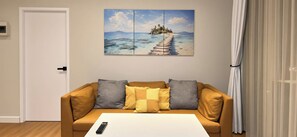 Ein Wohnzimmer mit einer Couch, einem Couchtisch und einem Gemälde von einer Strandansicht.