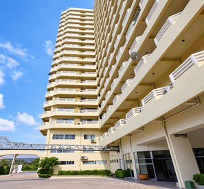 Ein mehrstöckiges Hotel mit Balkonen, einem überdachten Eingang und blauem Himmel.