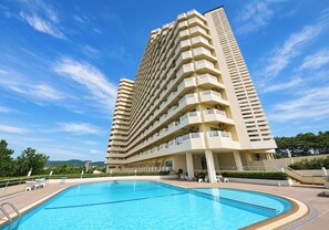 Ein Hochhaus-Hotel mit Schwimmbad davor.