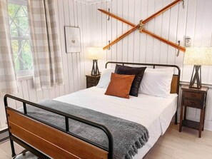 Une chambre à coucher avec un cadre de lit en bois, du linge de lit blanc et deux lampes de chevet.