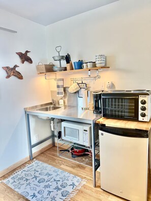 A compact kitchen with a built-in microwave, a coffee maker, and a small refrigerator. - Kari’s Lakeshore Loft - Minutes from Houghton (Chassell)