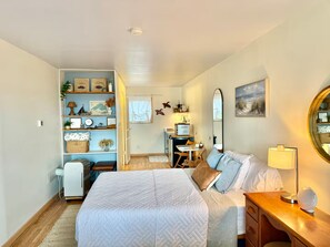 A bedroom with a bed, bedside table, dresser, and a built-in wardrobe with shelves. - Kari’s Lakeshore Loft - Minutes from Houghton (Chassell)