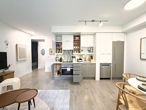 A modern kitchen with white cabinets, a built-in oven, and a stainless steel dishwasher. - Cozy 2BR • Gym+Parking • Rogers Centre | MTCC (Toronto)