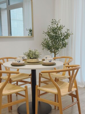 Een ronde eettafel met zes houten stoelen, een potplant en een vaas met bloemen.