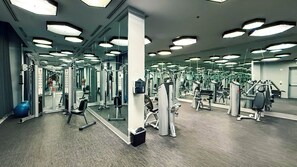Een sportschool met diverse fitnessapparaten, spiegels en verlichting.