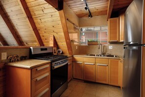 Eine Küche mit Holzschränken, einem Edelstahlkühlschrank und einem eingebauten Backofen.