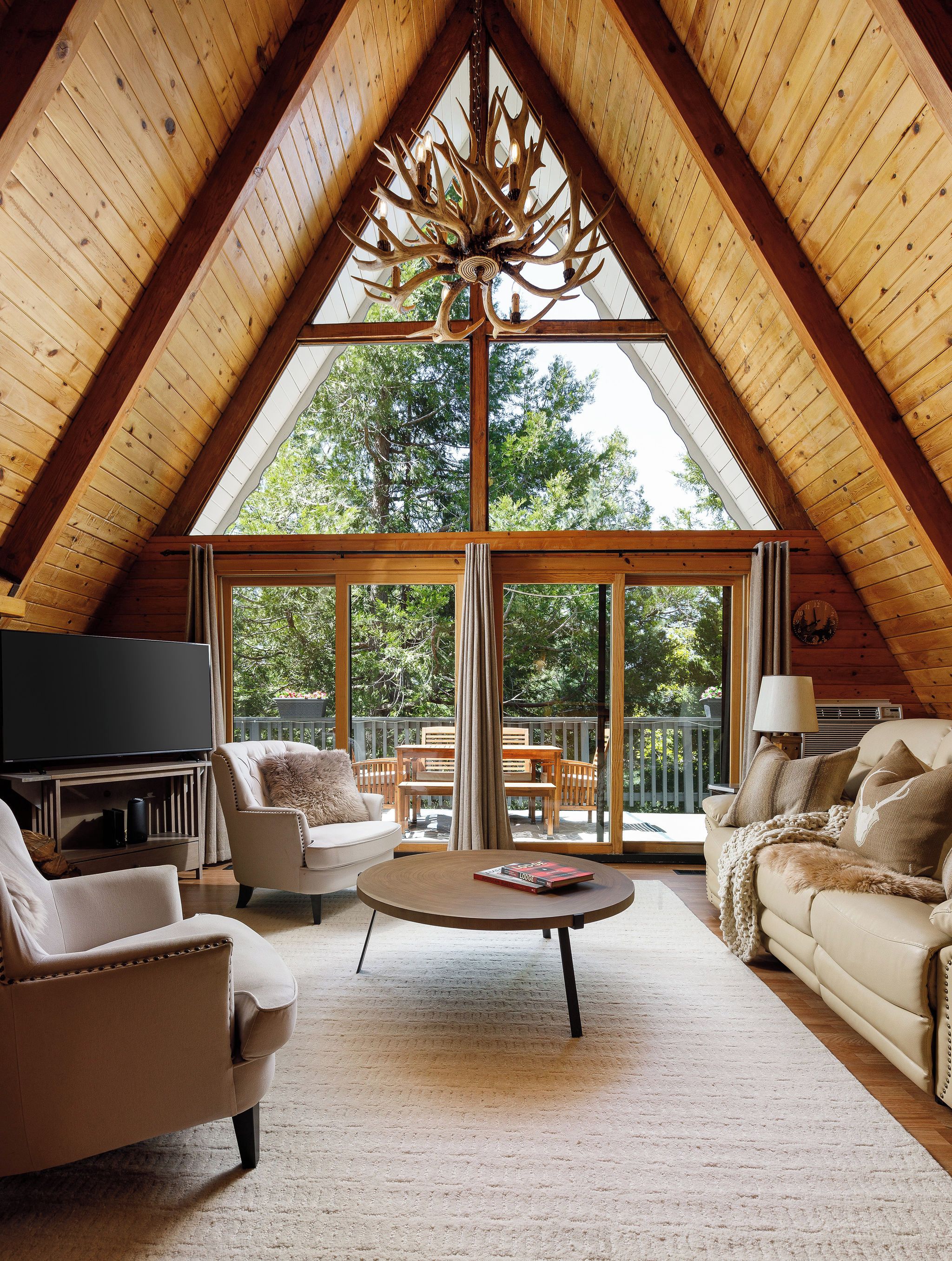 A spacious loft with a high ceiling, a large chandelier, and a cozy seating area with a flat-screen TV.