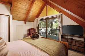Ein Schlafzimmer mit einem großen Bett, einem Sessel, einem Fernseher und Blick auf eine Terrasse.