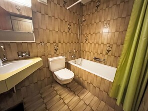 Et badeværelse med toilet, vask og badekar.