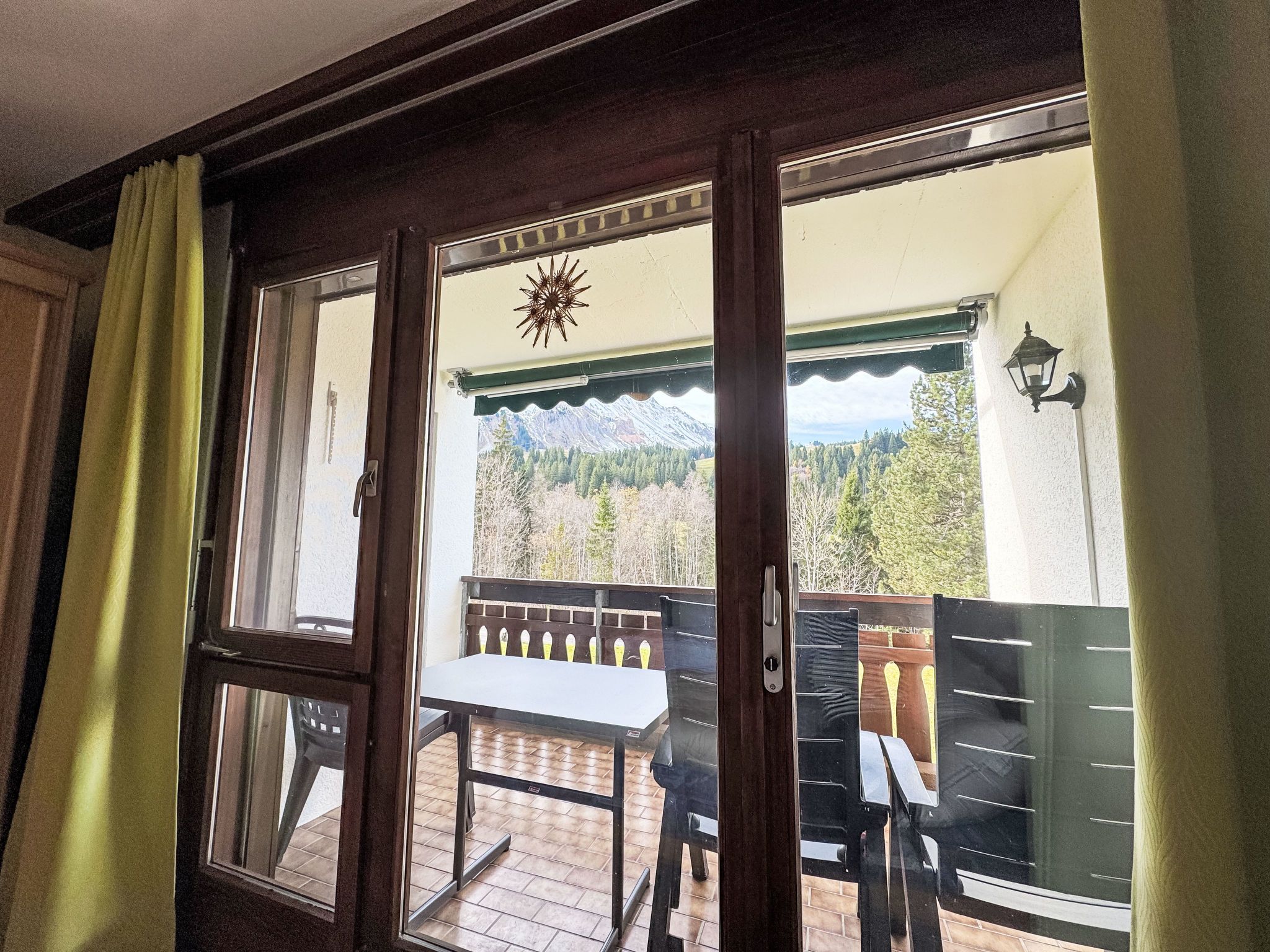 A room with a view of a mountain landscape through a window.