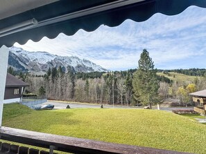 Vista de uma varanda com vista para uma área gramada e uma montanha ao fundo.