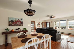 From the dining table, the view carries through the living room to the windows and the mountains beyond.