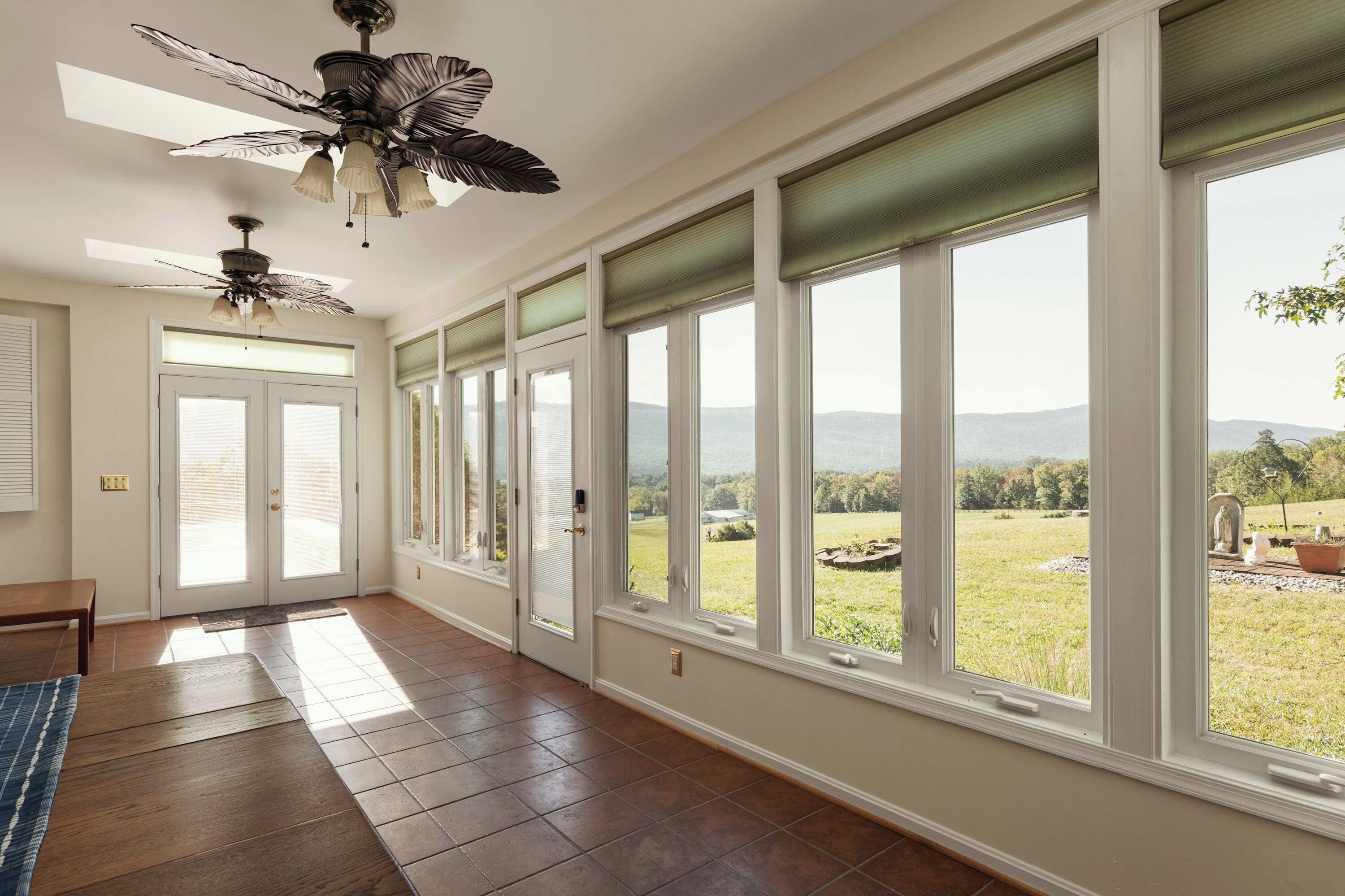 A spacious room with large windows, a ceiling fan, and a view of a landscape.