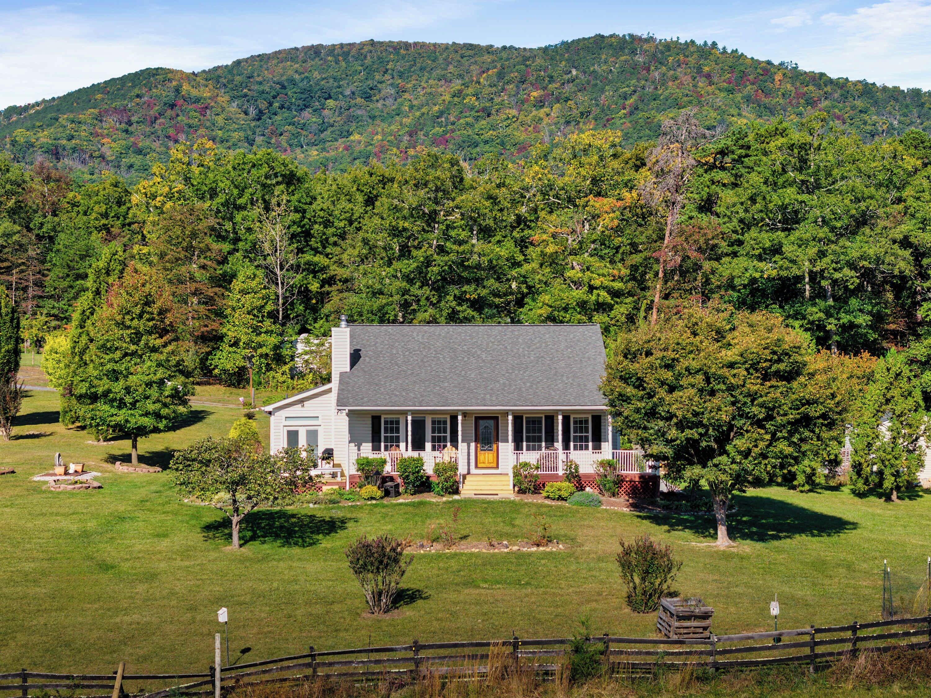 A two-story house with a porch, surrounded by a well-maintained lawn and trees.