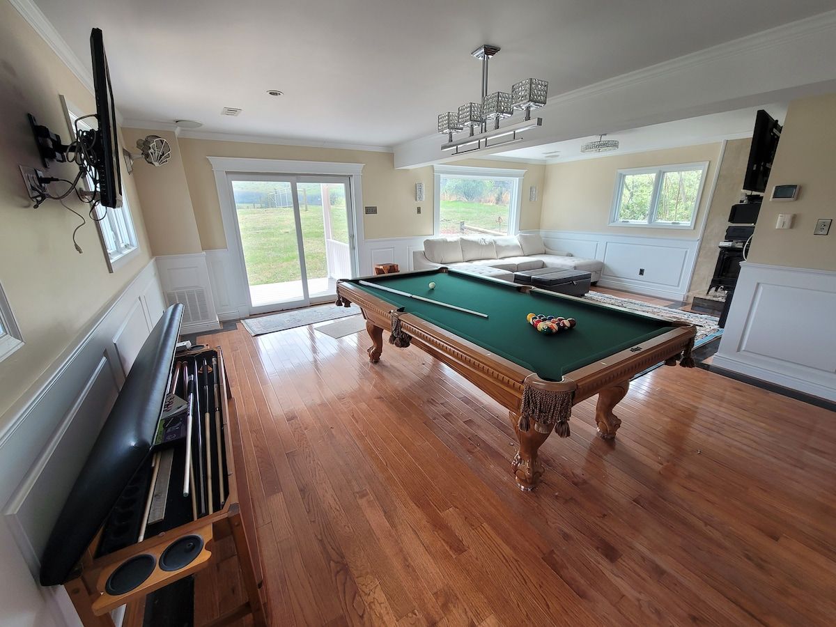 Una habitación amplia con mesa de billar, piano y soporte para billares.