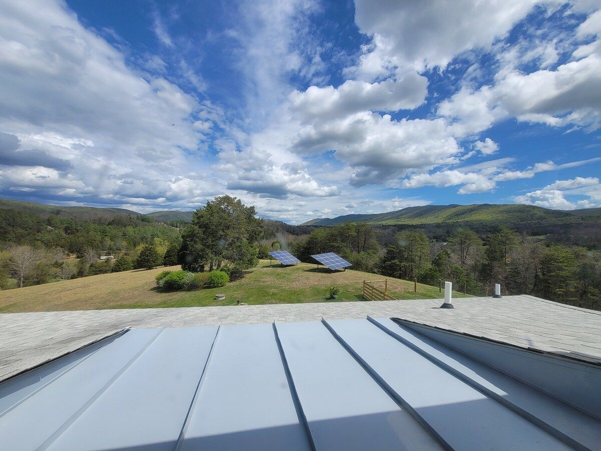A rooftop with solar panels and a view of a hilly landscape.