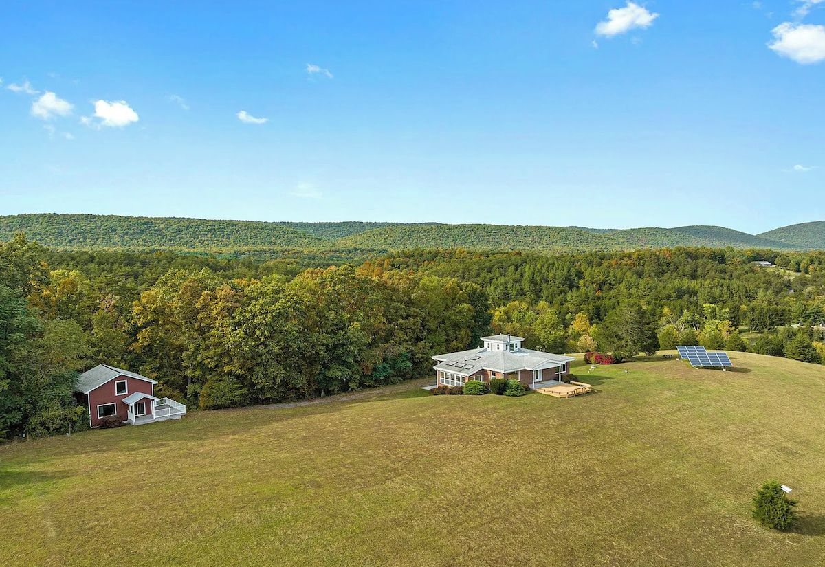A rural property with two main buildings, a barn, and a house with solar panels.