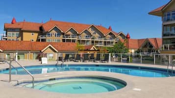 Ein Hotel mit Schwimmbad, mehreren Balkonen und einem roten Ziegeldach.