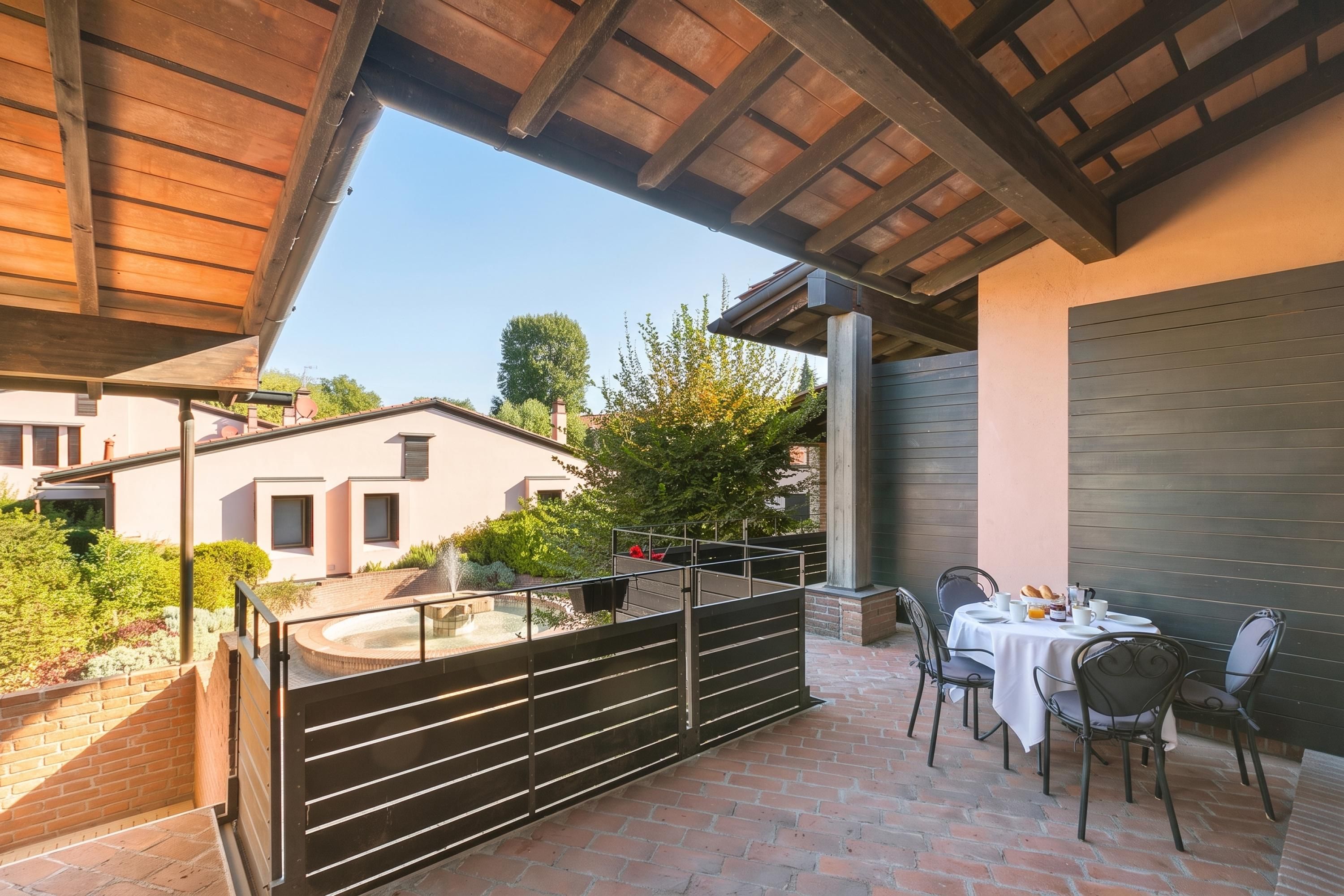 Un patio esterno coperto con pavimento in mattoni, un tavolo con sedie e vista su un edificio con un camino.