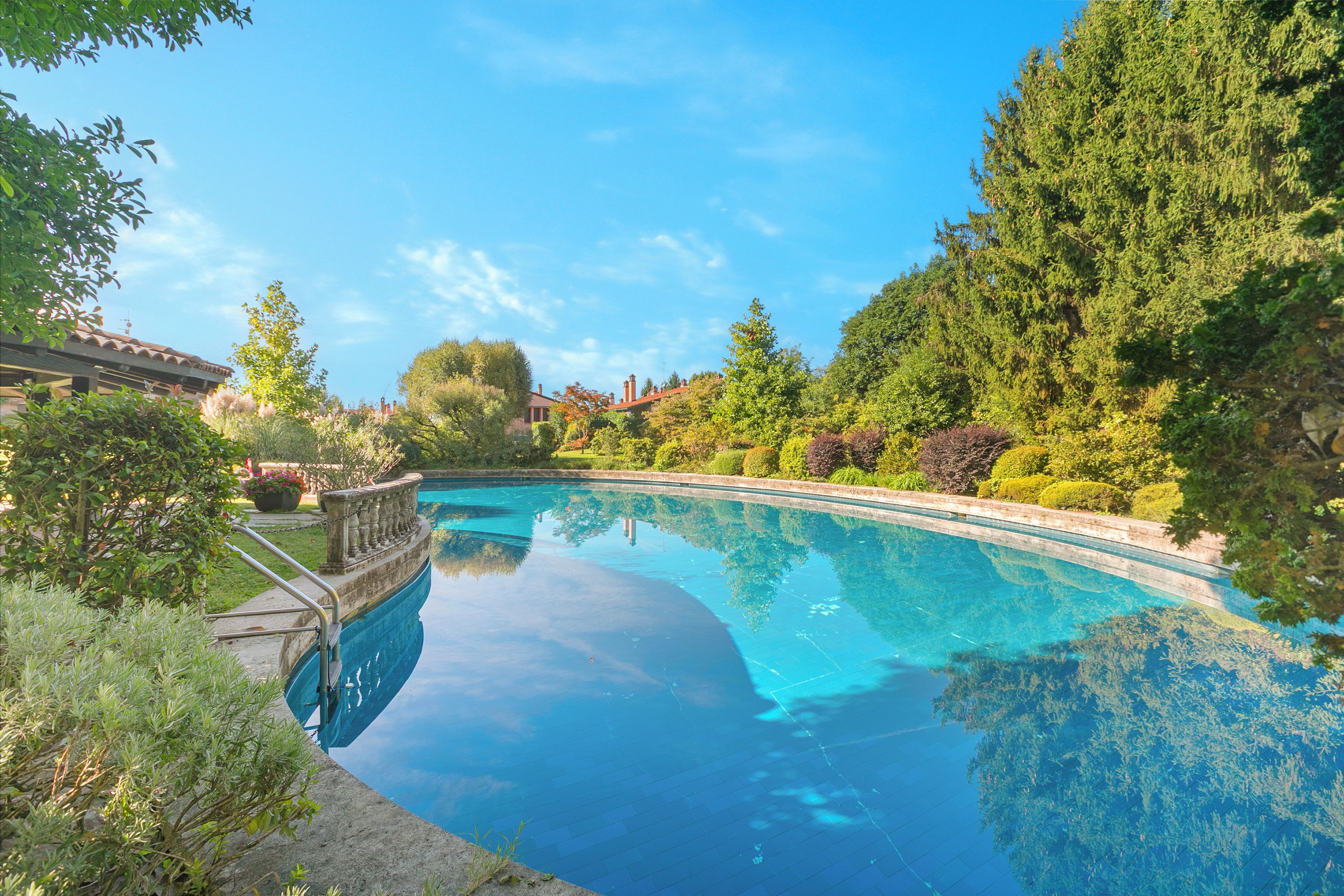 Una piscina limpida circondata da una vegetazione rigogliosa e un giardino curato.