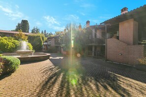 A courtyard with a fountain, brick buildings, and a clear sky. - Borgo Della Motta Swimming Pool &Golf, Travedona Monate, Italy (Travedona Monate)
