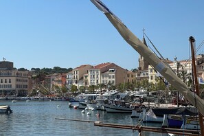 Un puerto deportivo con barcos amarrados, cielo despejado y edificios al fondo.