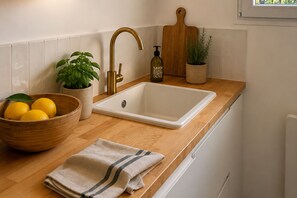 A kitchen with a wooden countertop, a white sink, a bottle of olive oil, a bowl of lemons, a potted basil plant, and a cutting board. - Sanary Apt N2, Sanary-sur-Mer, France (Sanary-sur-Mer)