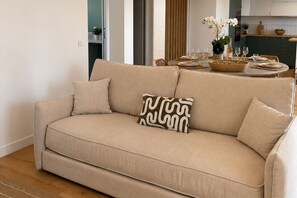 A beige sofa with a patterned pillow in a living room with a wooden floor. - Sanary Apt N1, Sanary-sur-Mer, France (Sanary-sur-Mer)